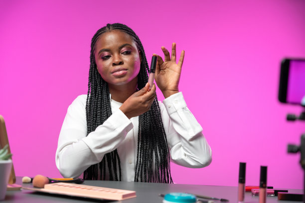 一位年轻迷人的非裔美国美女博主在一个亮粉色背景的录音棚录制唱片图片下载