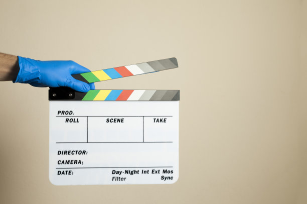 手戴着蓝色外科手术手套，在中性背景下击打电影拍板。图片下载