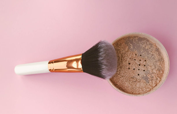 粉刷在明亮的粉红色背景。洗脸粉和刷子。松散的哑光粉，以配合皮肤。用于化妆和色调创造的矿物粉图片下载