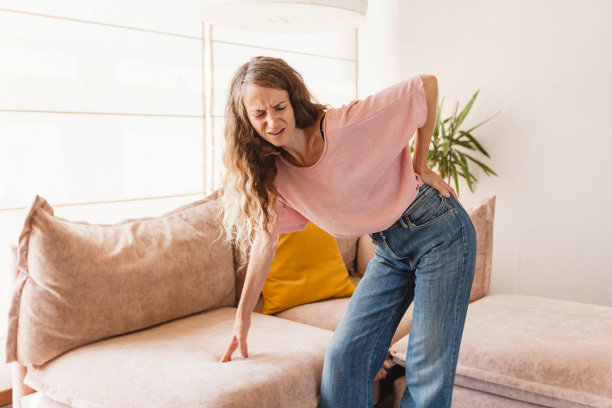 成年女子托着腰站着，疼痛难忍图片下载