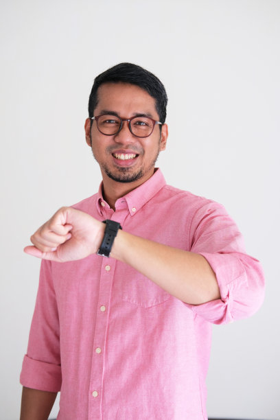 成年亚洲人微笑自信时，看他的手臂手表图片下载