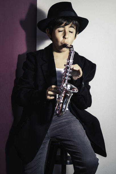 孩子在家充满激情地演奏萨克斯，打扮成爵士音乐家图片下载