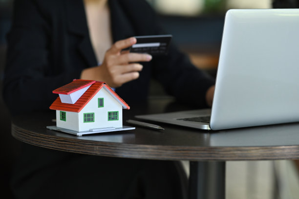 一张被笔记本电脑、文书、计算器和房子模型包围的工作桌子的照片。图片下载