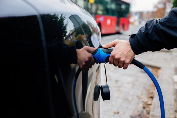 手持电动汽车充电器的男子图片下载