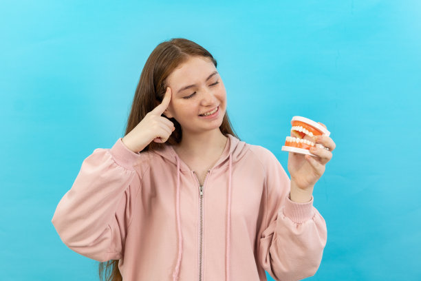 牙齿美丽的微笑年轻女子与牙套高兴的情绪与白色的牙齿增加自信健康的蓝色背景孤立，快乐有趣的少女刷牙，健康的概念，图片下载