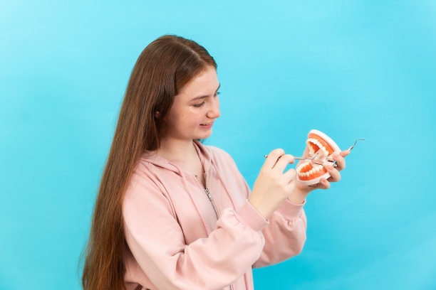 牙齿美丽的微笑年轻女子与牙套高兴的情绪与白色的牙齿增加自信健康的蓝色背景孤立，快乐有趣的少女刷牙，健康的概念，图片下载