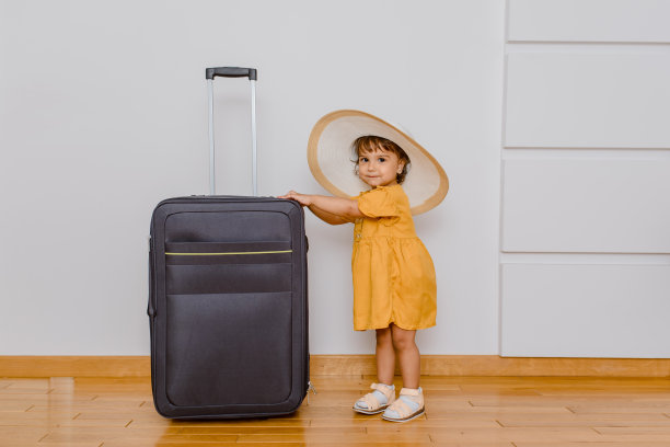 一个戴着白色特大号帽子的小女孩站在一个大箱子旁边。图片下载