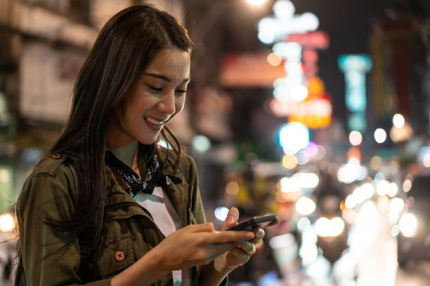 亚洲有吸引力的女人背包客聊天电话，而走在城市。美丽的女性游客旅行者独自在街上旅行，使用智能手机享受花时间在假期假期旅行在夜间道路图片下载