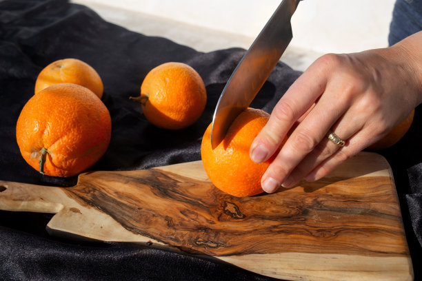 橙子切片过程的照片。一位妇女在木板上用刀切橘子图片下载