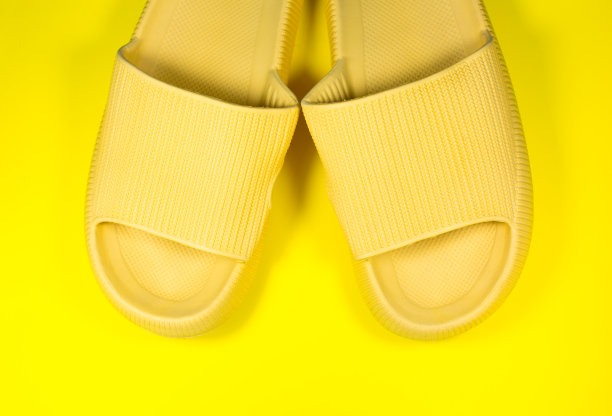 黄色背景上的黄色夏季拖鞋。一双室内鞋。极简主义创造性的照片。图片下载