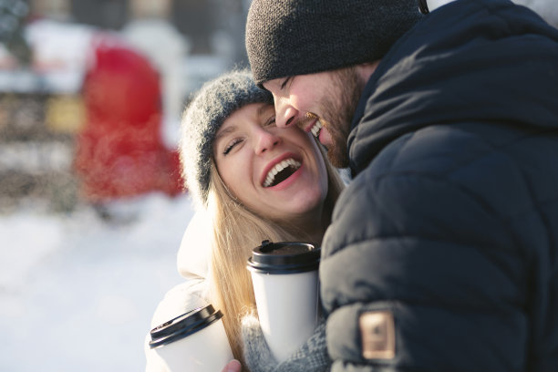 一对幸福的夫妇的特写:男人和女人拥抱和笑在一个冬天的雪公园。图片下载