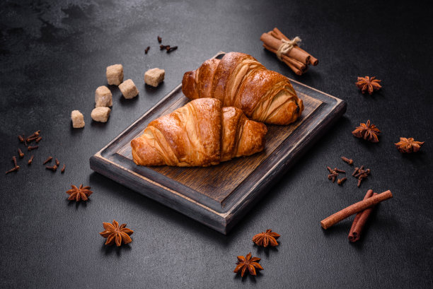 美味、新鲜、酥脆的羊角面包铺在深色混凝土上。美味的早餐图片下载