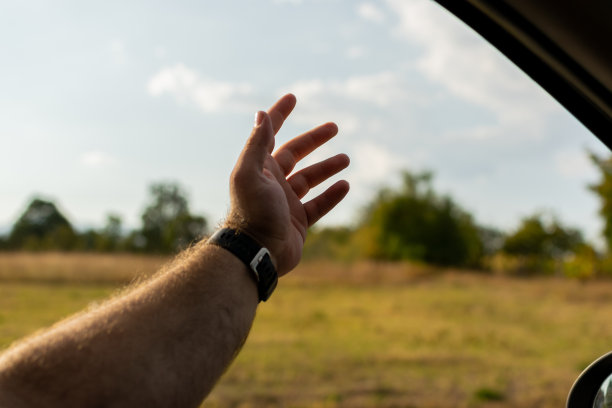 把手伸进车窗，感受空气，感受自由，享受阳光明媚的夏日，在绿油油的田野和树木环绕的开阔道路上行驶。图片下载