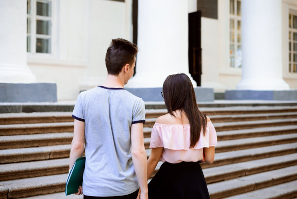 年轻的情侣在大学大楼附近，手牵着手，后视镜图片下载