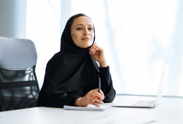 穿着阿拉伯长袍在办公室工作的阿拉伯美丽女人图片下载