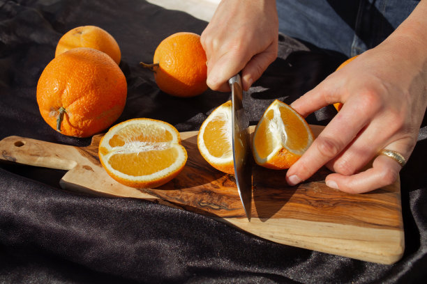 橙子切片过程的照片。一位妇女在木板上用刀切橘子图片下载