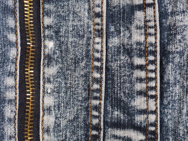 特写牛仔布与接缝和锁。破旧不堪的牛仔裤。金属青铜黄色锁带流道。垂直接缝。图片下载