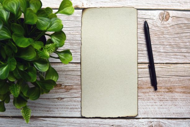 木桌上放着焦边棕色纸、笔和智能手机。空白文本图片下载