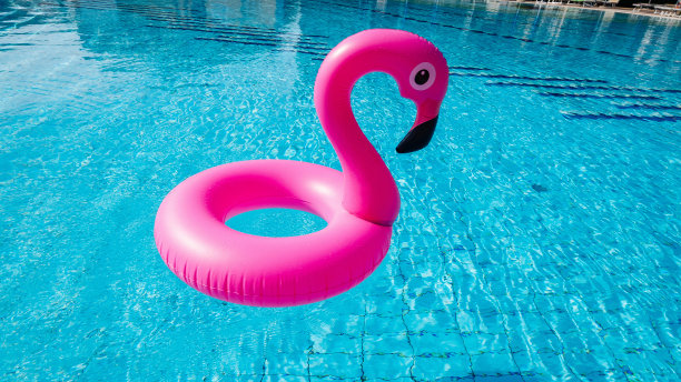 塑料火烈鸟。粉红色充气火烈鸟在泳池水为海滩背景。时尚的夏天的概念。图片下载