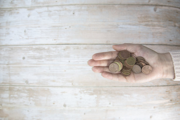 手里拿着一堆钱，在木头的背景上，手里拿着欧元硬币。捐赠、储蓄、筹款慈善、家庭理财计划理念、金融危机理念。前视图。本空间图片下载
