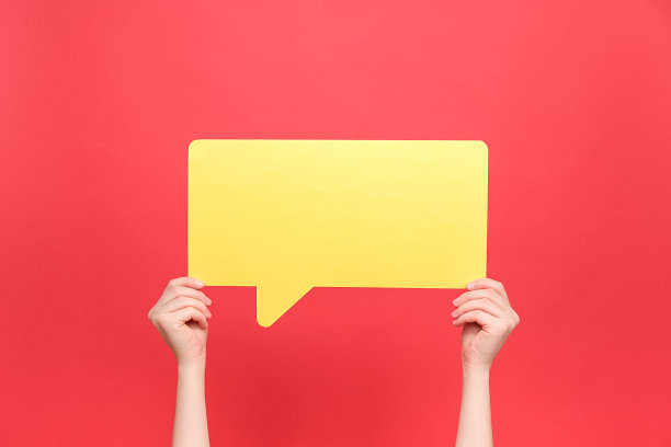 女性的手握大的大空黄色的演讲气泡的特写，孤立在蜡笔红色背景工作室与宣传内容或设计复制空间。对话与概念图片下载