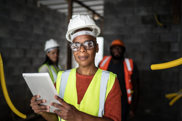 图为一名女工程师在施工现场与同事们一起使用数码平板电脑的照片图片下载