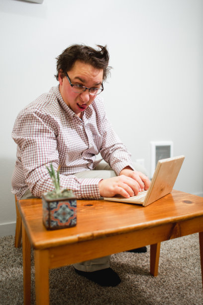使用木制小桌子和木制笔记本电脑的书呆子办公室职员图片下载