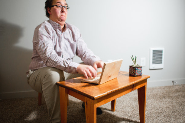 使用木制小桌子和木制笔记本电脑的书呆子办公室职员图片下载