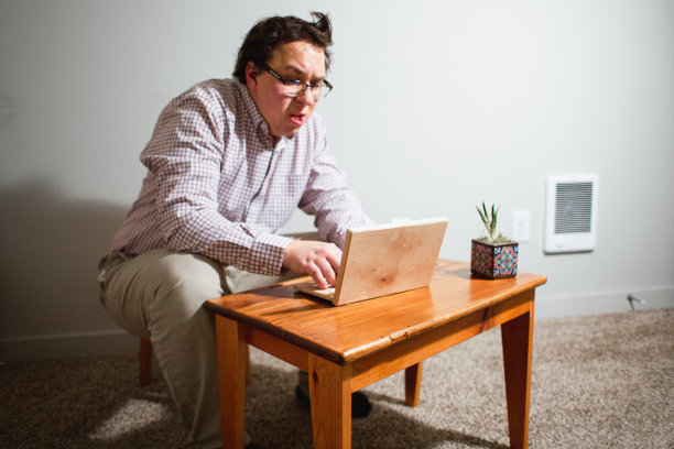 使用木制小桌子和木制笔记本电脑的书呆子办公室职员图片下载