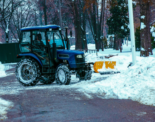 一辆蓝色的拖拉机在大雪后清扫城市的街道和道路。图片下载