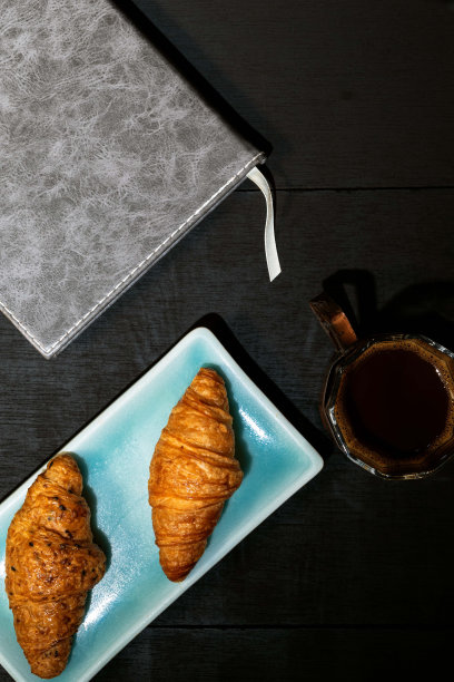 早餐是盘子里的羊角面包和木桌上的咖啡。图片下载