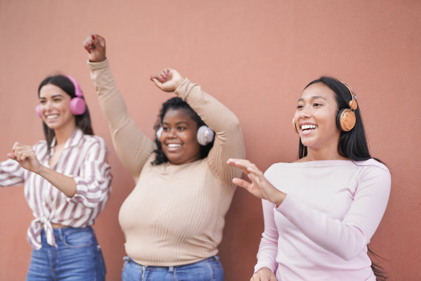 年轻的多种族女性用无线耳机随着音乐播放列表跳舞图片下载