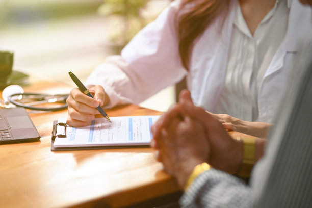 年轻聪明的医生坐在医生的工作桌前为老年病人诊断和提供建议的照片。图片下载