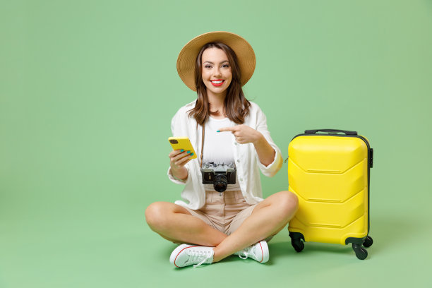 全长旅行者有趣的游客女人在休闲服装帽子拿手提箱点在手机上坐孤立在绿色背景乘客旅行国外周末度假航空飞行旅行概念图片下载