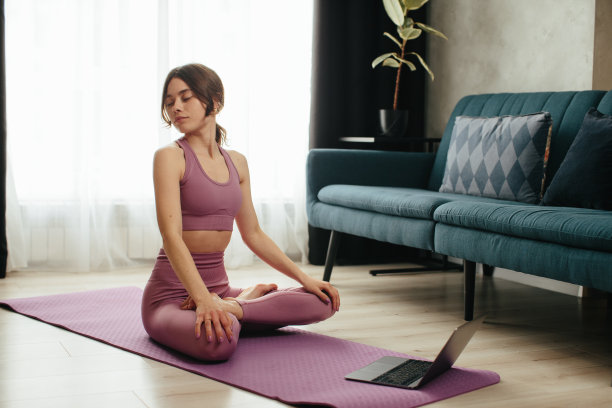 有吸引力的年轻女子做瑜伽伸展瑜伽在线在家里。自我隔离是有益的，在互联网上娱乐和教育。健康的生活方式的概念。图片下载