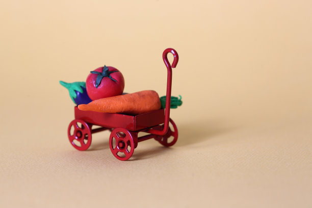红色的手推车载着收获的蔬菜，在粉红色的背景下隔离开来图片下载