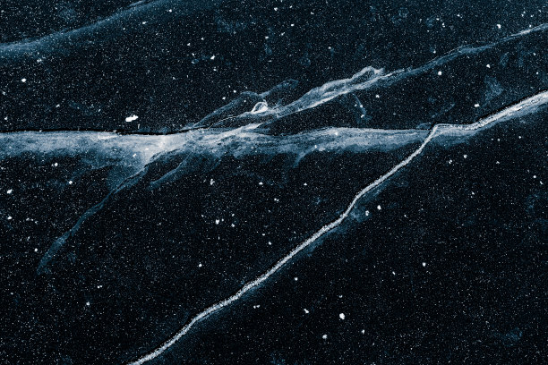 透明的冰面表面与黑色背景上的裂缝。图片下载