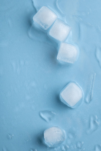 蓝色背景上的冰块和水滴。图片下载