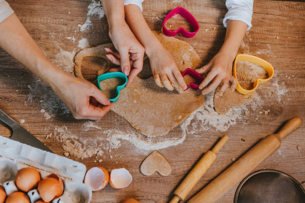 与父母切割黑麦面团心形饼干的小女孩的俯视图图片下载
