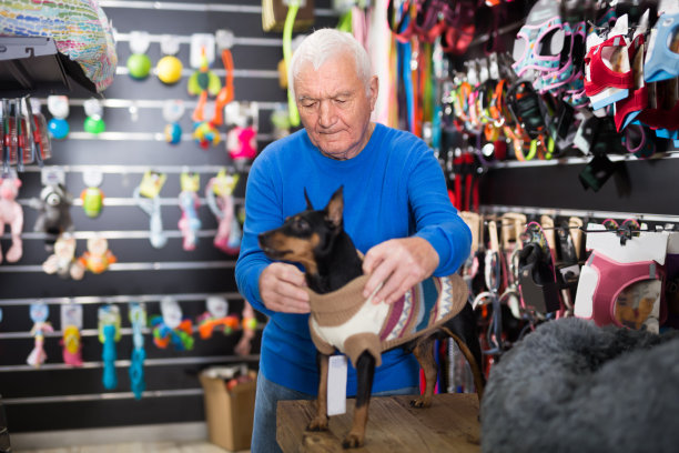 退休老人在宠物店给他的狗穿上冬装图片下载