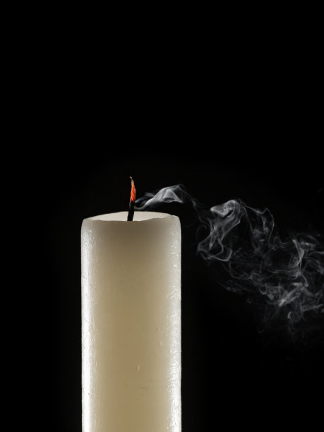 有燃烧的灯芯和烟的蜡烛，孤立在黑色的背景上图片下载