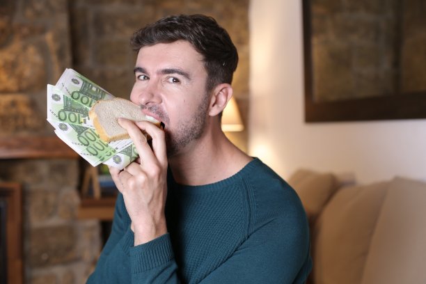 一个男人在享用装满欧元的三明治图片下载