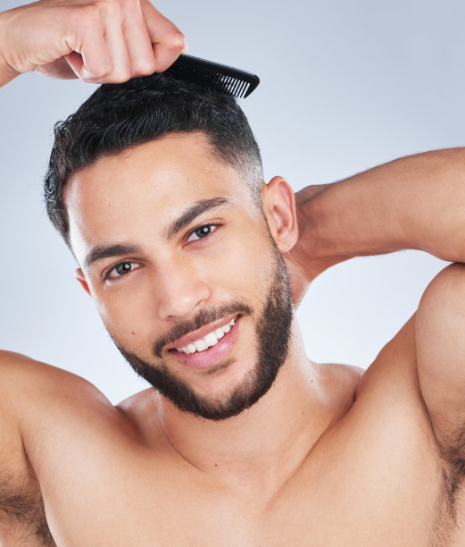 一个英俊的年轻人在灰色的背景下梳头发图片下载