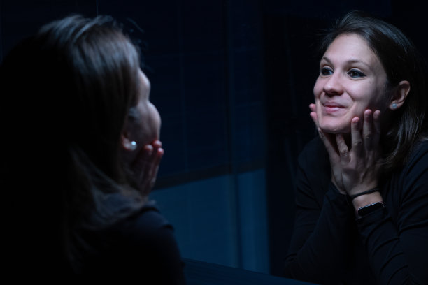 一个年轻的成年女性在化妆前对着镜子看自己的脸图片下载