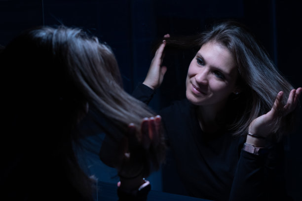 一个年轻的成年女性在化妆前对着镜子看自己的脸图片下载