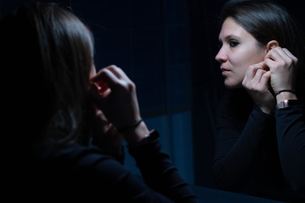 一个年轻的成年女性在化妆前对着镜子看自己的脸图片下载