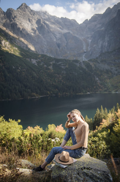 年轻女子徒步旅行时坐在一块岩石上图片下载