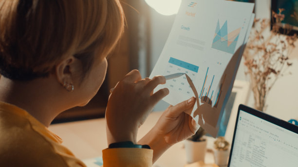 年轻的亚洲自由职业女性晚上在家里的客厅里使用笔记本电脑和平板电脑。在家工作的概念。图片下载