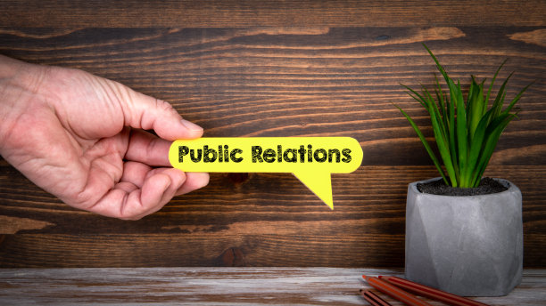 公共关系。黄色的语音泡泡在一个男人的手中，在一个木制的背景上图片下载