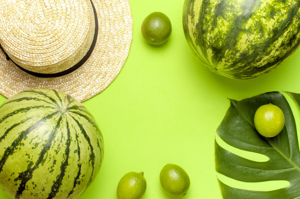 成熟的西瓜浆果，夏季草帽，整个酸橙，热带叶怪物在绿色背景俯视图平躺。绿色条纹整西瓜。夏天明亮的背景。最小的水果的概念图片下载